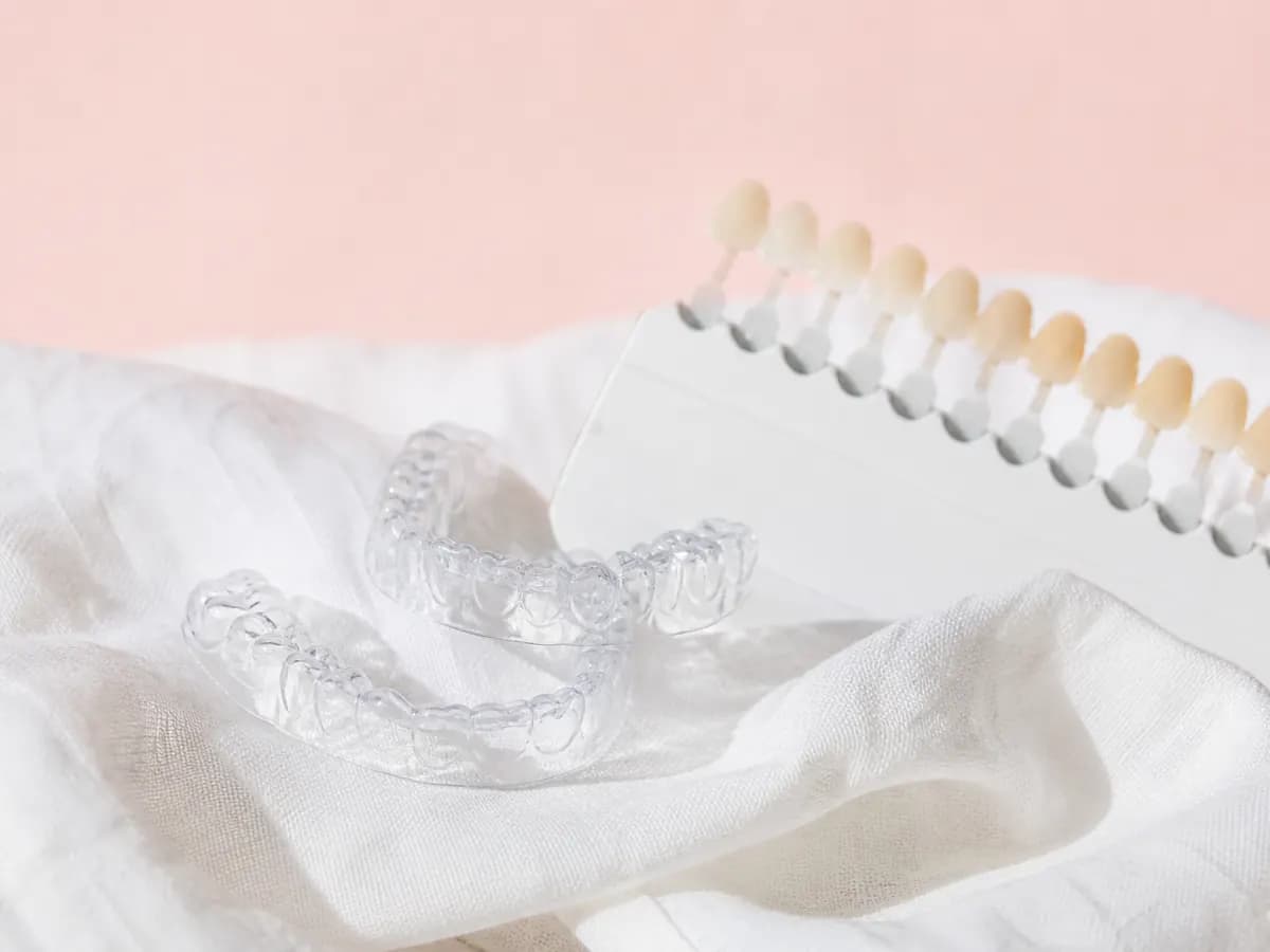 Clear whitening trays and a tooth shade guide on a white cloth.